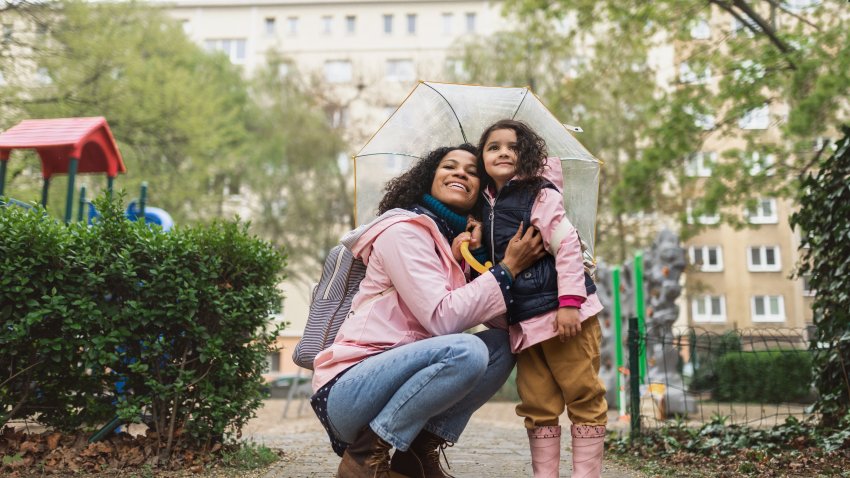 Stock image shows woman and child under umbrella.