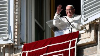 Pope Francis waves out a window