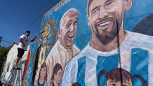Roberto Coria preserves a mural depicting Pope Francis and soccer star Lionel Messi in Buenos Aires, Argentina, Wednesday, Feb. 19, 2025.
